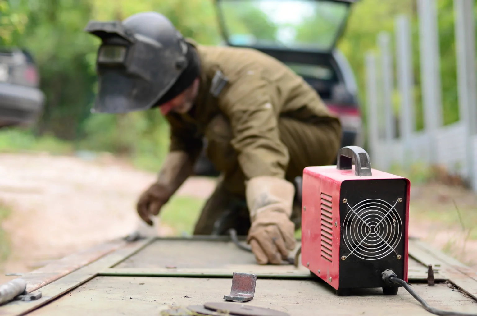 Welder repairing a metal surface outdoors